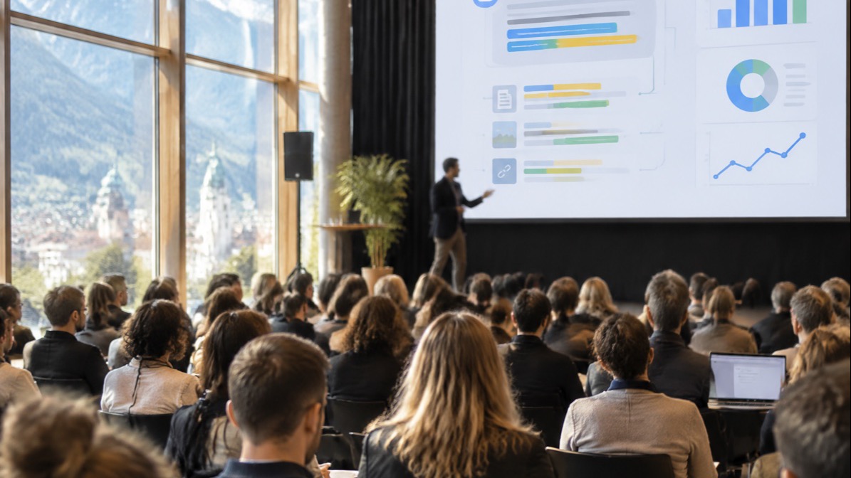 Symbolbild: Publikum in einem hellen Festsaal mit Bergblick, vorne ein Sprecher vor einer Leinwand mit Diagrammen zu KI-Antworten